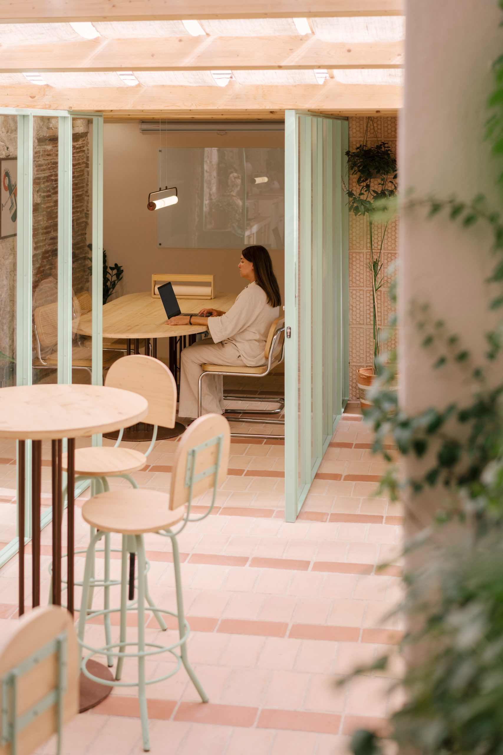 Espacio contemporáneo de arquitectura interior en Barcelona con patio integrado, carpinterías verdes y zona de trabajo diseñado por Oliver Segura Arquitectura.