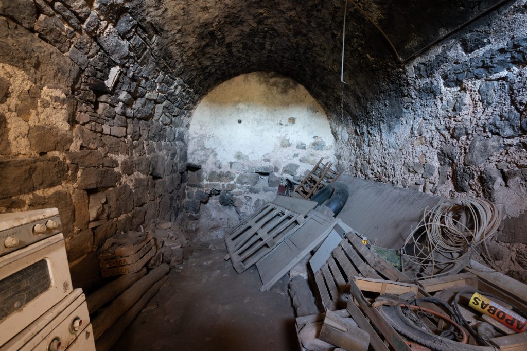 Fotografía de un interior con carácter: muros de piedra, vigas, pavimento antiguo, arcos o espacios con potencial.