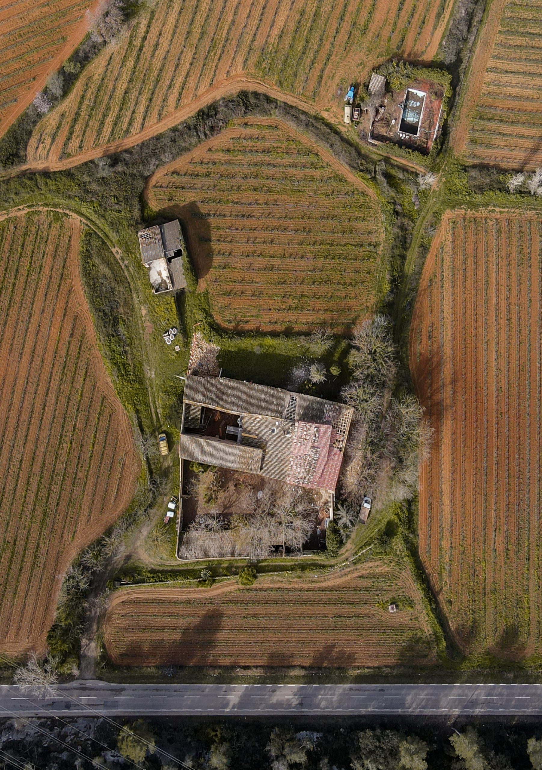 Vista aérea de una finca singular con masía histórica y terrenos agrícolas en Cataluña.
